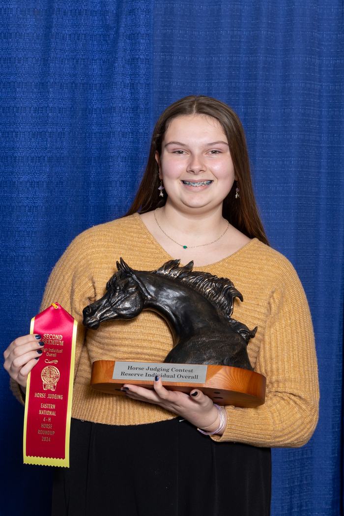 Person holding horse-head trophy labeled "Reserve Individual Overall" and red ribbon "Second Premium".