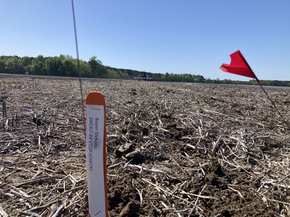 A stake in a field noting a trial is taking place.