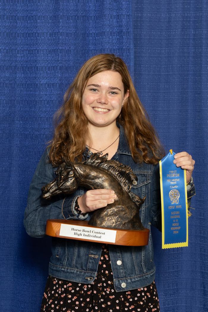 Person holding horse-head trophy labeled "Horse Bowl Contest High Individual" and blue ribbon