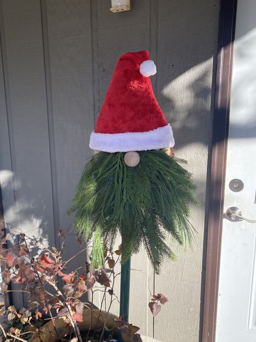 A gnome decoration made from a santa hat and live greenery.