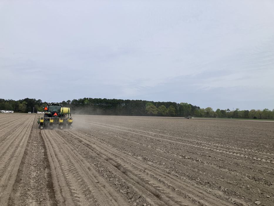 A tractor plowing rows in a field.