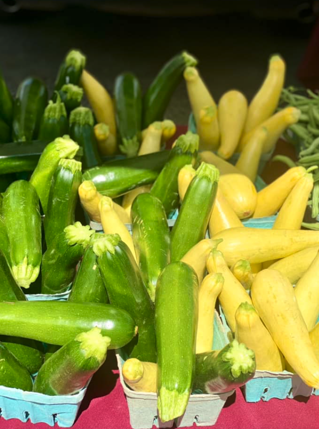 Green zucchini and yellow summer squash in cardboard baskets on table