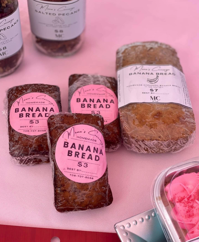 Wrapped banana bread loaves with pink labels reading "BANANA BREAD $3" and one larger loaf