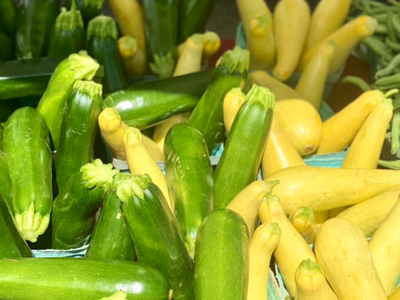 Green zucchini and yellow summer squash in cardboard baskets on table