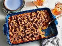 Rectangular blue baking dish with fruit crumble, one portion scooped out and serving spoon