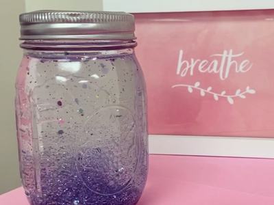 Glass jar with purple glitter liquid on pink surface; framed sign reads "breathe"