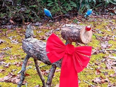 Wood log reindeer with red bow and colored light-bulb antlers on mossy ground