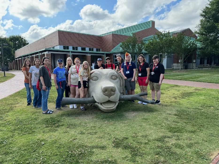 group portrait outside of vet school standing around the statue of a dog