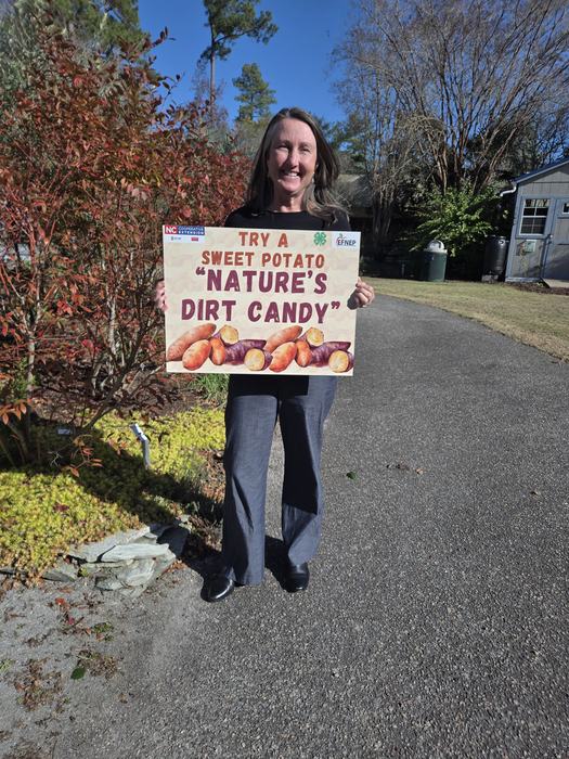 Extension CED Amy Mead holding a sweet potato sign