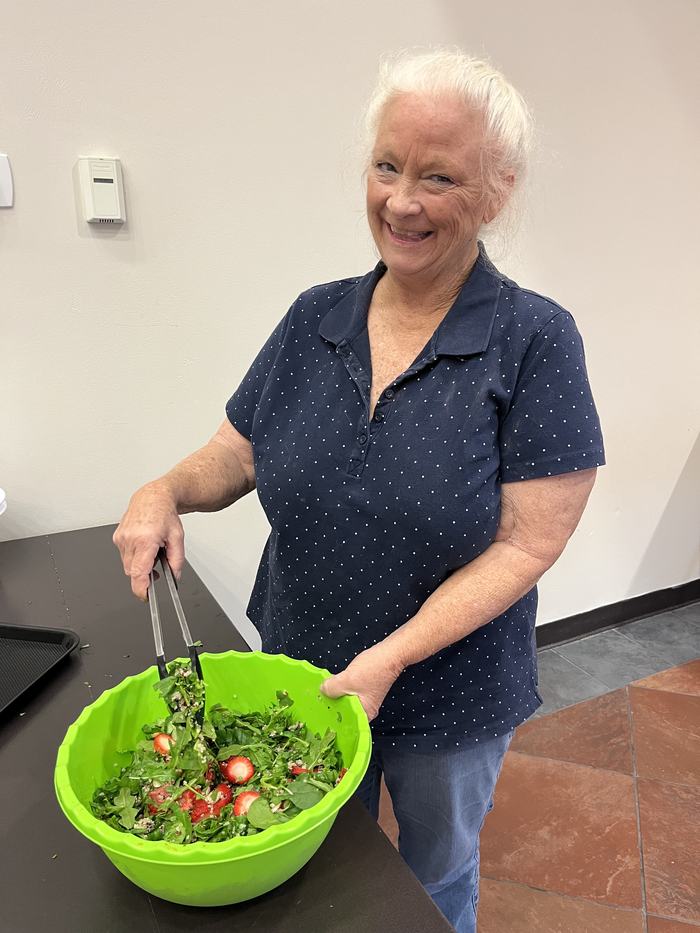 participant smiling and showing bowl of salad with strawberries