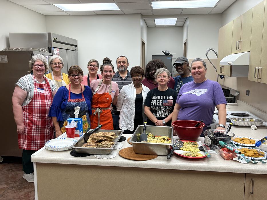 group photo of participants and FCS agent Rachel Ezzell standing around the dishes prepared in the workshop