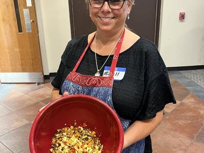 woman smiling while wearing an apron and holding a bowl