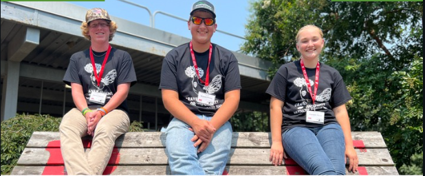 Three 4-H participants, Connor Howard, Matthew Peluso, and Elizabeth Peluso pose smiling in their poultry t-shirts