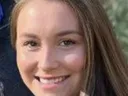 Young woman with long brown hair smiling, close-up portrait