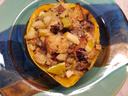 squash filled with sauase and onions on a green plate with blue and brown stripes in center