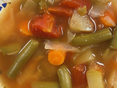 Bowl of vegetable soup with carrots, green beans, potatoes, and tomatoes