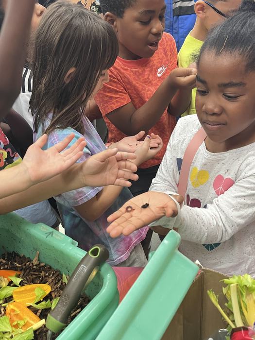 young student holding a worm in the palm of her hand