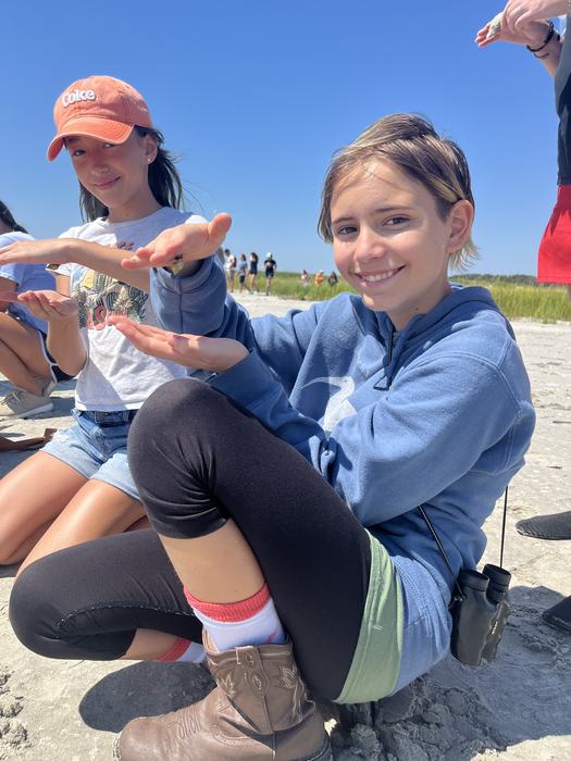 youth holding a snail upside down on the palm of her hand