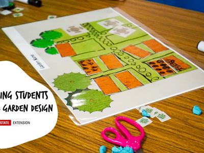 Garden design plan on table with pink scissors; text: 'Engaging Students in School Garden Design'
