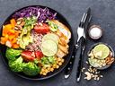 Buddha bowl dish with chicken fillet, brown rice, avocado, pepper, tomato, broccoli, red cabbage, chickpea, fresh lettuce salad, pine nuts and walnuts. Healthy balanced eating. Top view