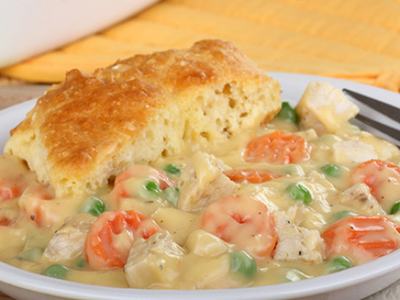 Biscuit with creamy chicken and vegetable stew (peas, carrots, potatoes) on a plate