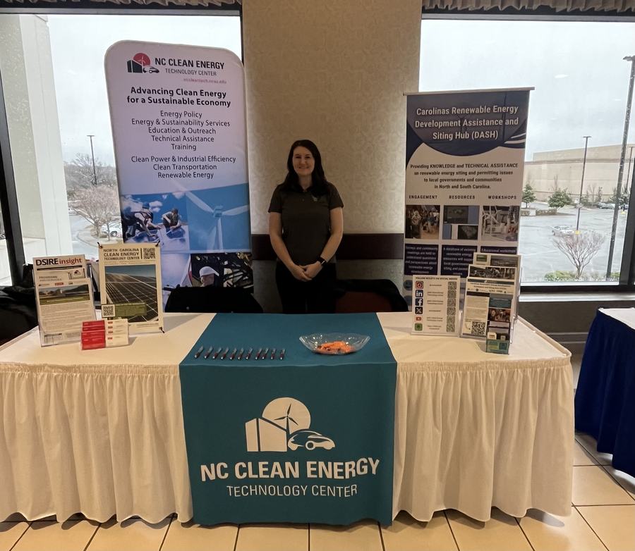 A woman stands at a booth for NC Clean Energy