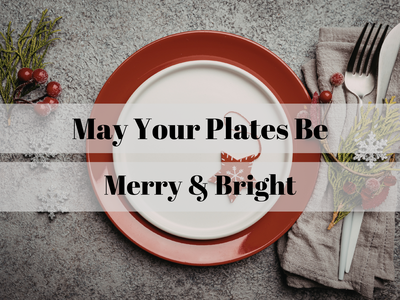 Holiday place setting with red plate, star ornament and text "May Your Plates Be Merry & Bright"