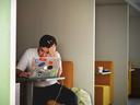 A man working on a laptop, holding his head in a gesture indicating anxiety and stress.