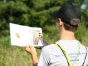 Person in cap holds a color-chart booklet; shirt text: "Thank You Envirothon Sponsors" and "Smithfield"