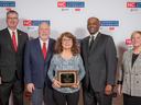 Five people at NC Cooperative Extension event; center woman holds an award plaque.