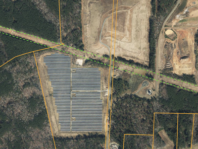 Aerial view of large solar panel field within parcel boundaries adjacent to a road