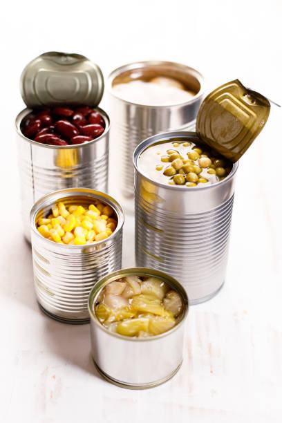 Different kinds of vegetables in cans on kitchen table background.