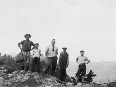 3 boys and two men stand of a rock in Edgemont.