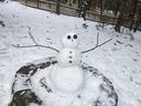 A small snowman in a fire pit surrounded by snow.