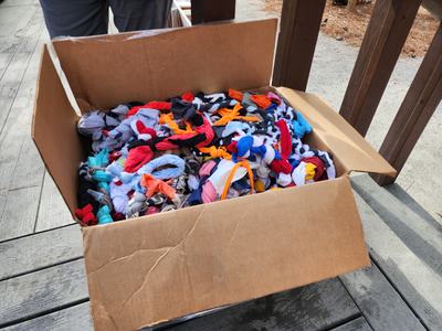 Open cardboard box filled with colorful tied fabric strips on wooden deck