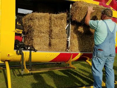 photo of a man loading hay into a helicopter