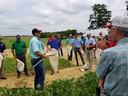 Group of people in a field gathered around a man holding insect nets