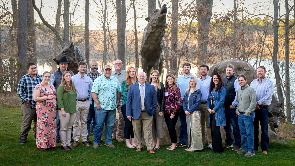 Group of 20 people standing outdoors in front of large wolf sculptures