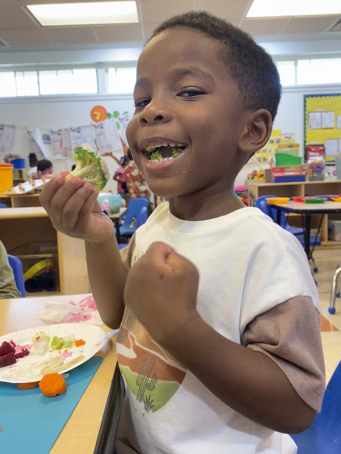 A child eats fresh broccoli.