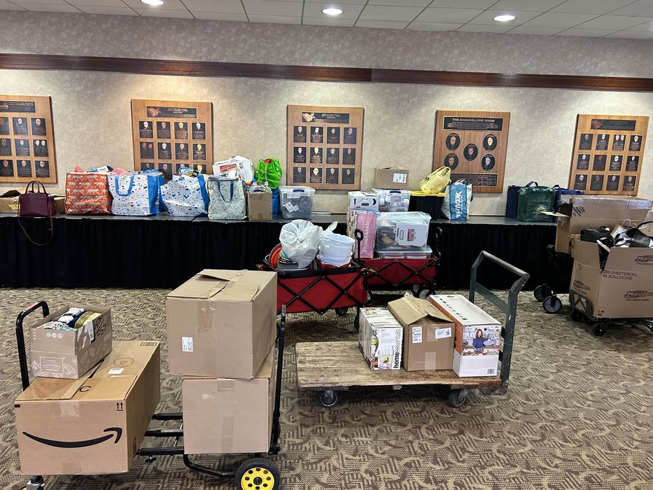 Stacked boxes and bags on carts and a table in a conference room
