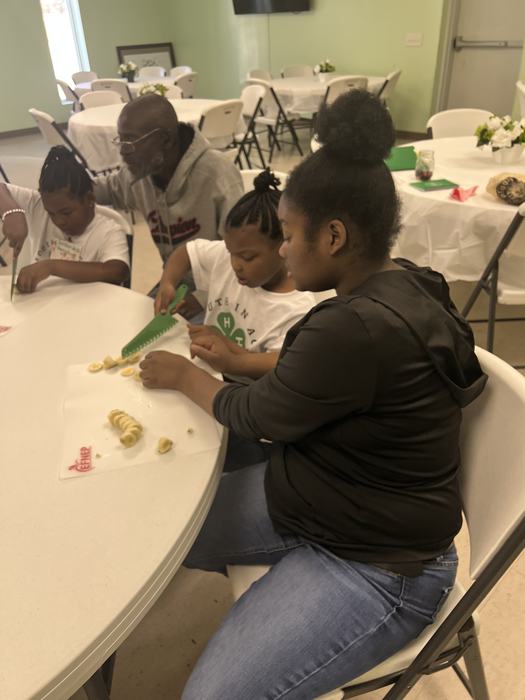 Two kids cut fruit together.