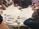 Children and teens gathered around a table sorting picture cards and a booklet.
