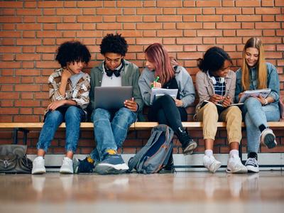 Kids on a bench with books and computers