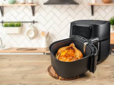 A whole chicken cooked inside an air frier. Air fryer machine fried in kitchen.