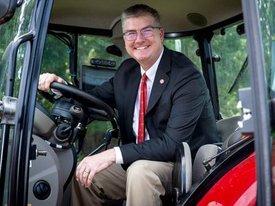 Garey Fox, dean of NC State University's College of Agriculture and Life Sciences, sits in a tractor.