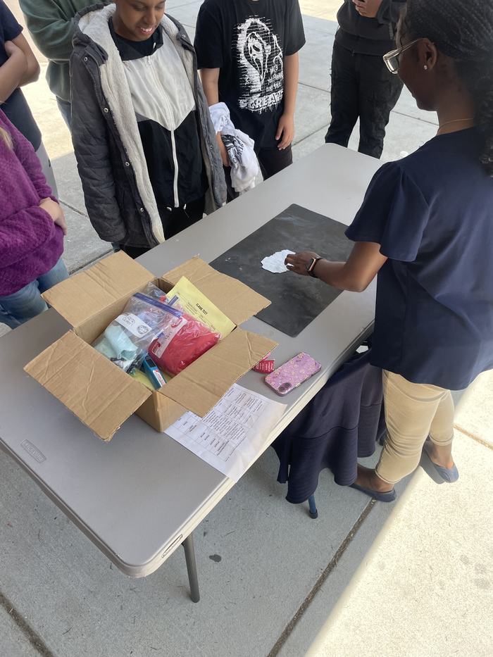 Teenagers stand around a demonstration table.
