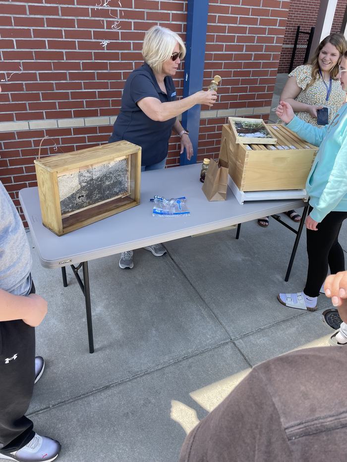 A woman shows off the tools of a beekeeper.