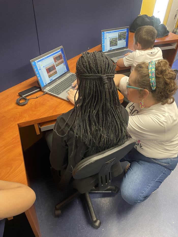 A woman helps a child with their video game.