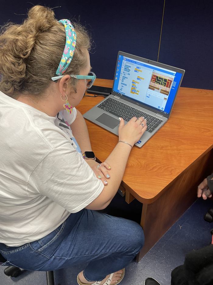 A girl creates a game on a laptop.