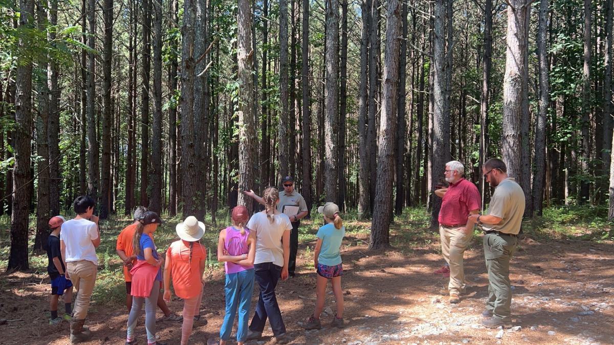group of students standing in front of trees. 
